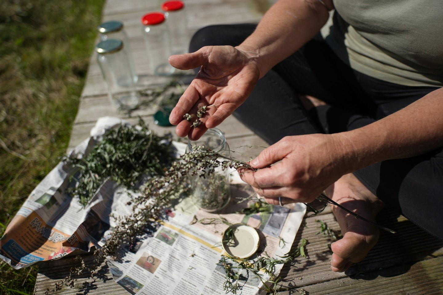 Une personne effeuille des herbes sur une planche en bois.
