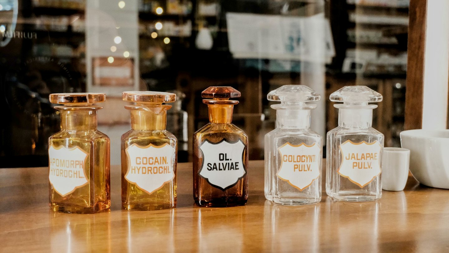 Cinq pots de pharmacie anciens sur un comptoir en bois poli.