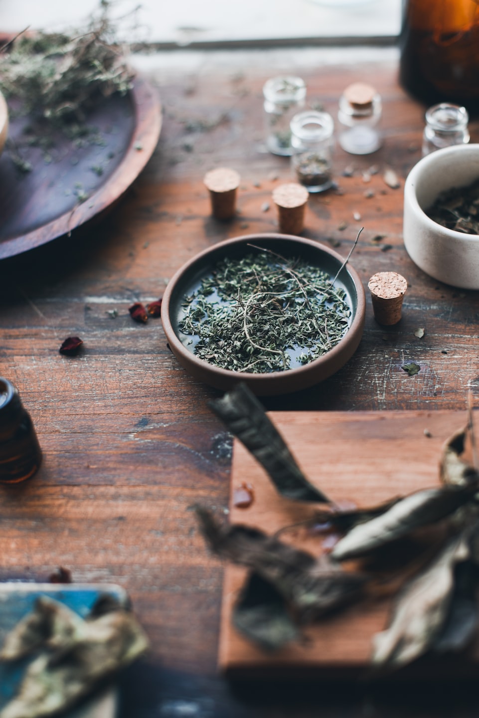Herbes séchées et flacons d'apothicaire disposés sur une table en bois.