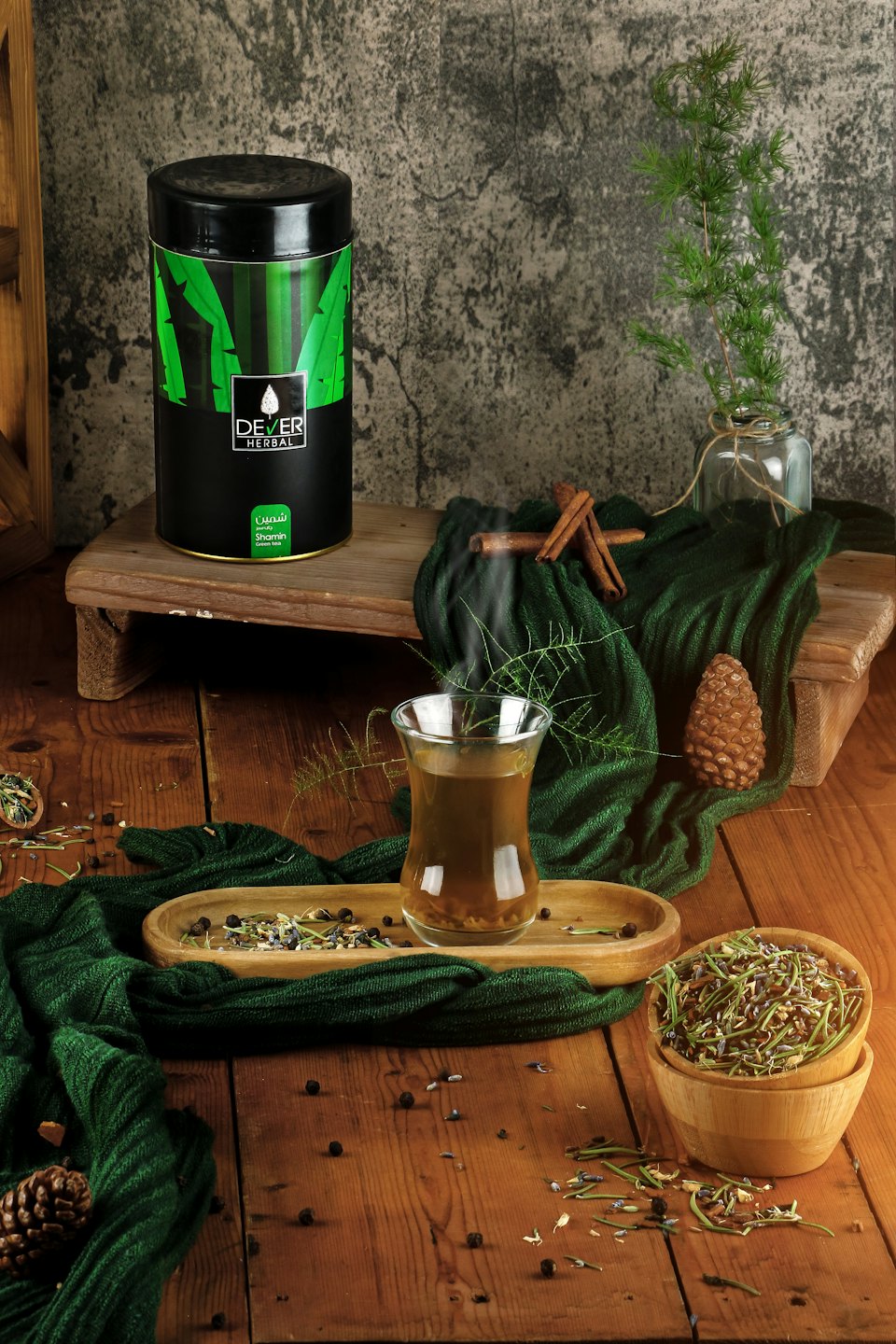 Une boîte à thé et un verre fumant sont posés au milieu d'herbes éparpillées.